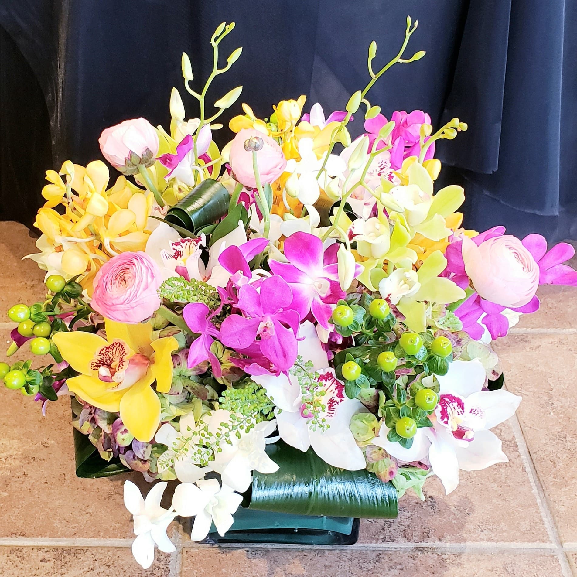 Jungle Jewels tropical arrangement with orchids and monstera