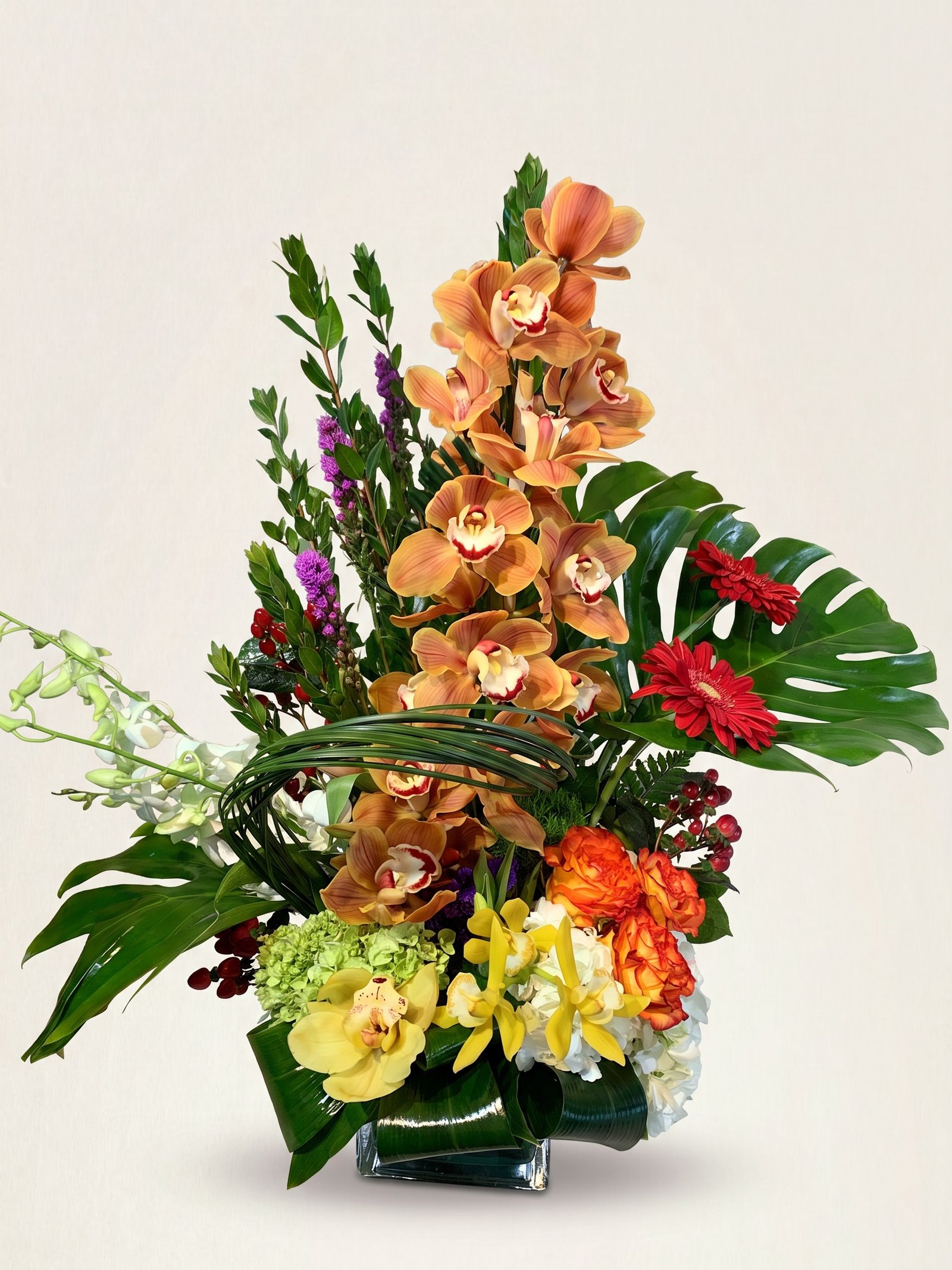 Orquídeas cymbidium altas color cobre con rosas naranja y una gerbera roja