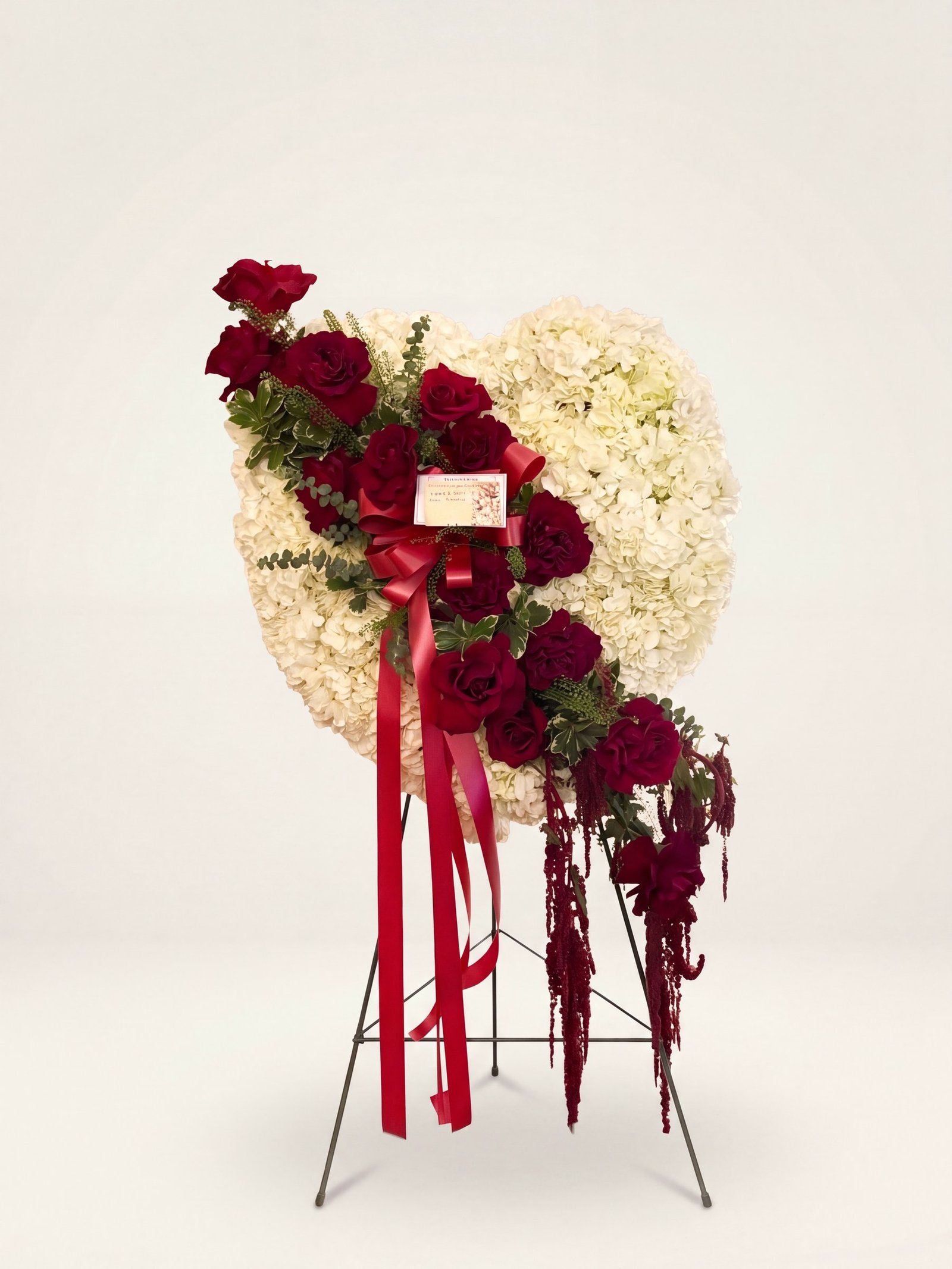 Funeral heart of white hydrangea with a bold diagonal of red roses and trailing amaranthus on an easel