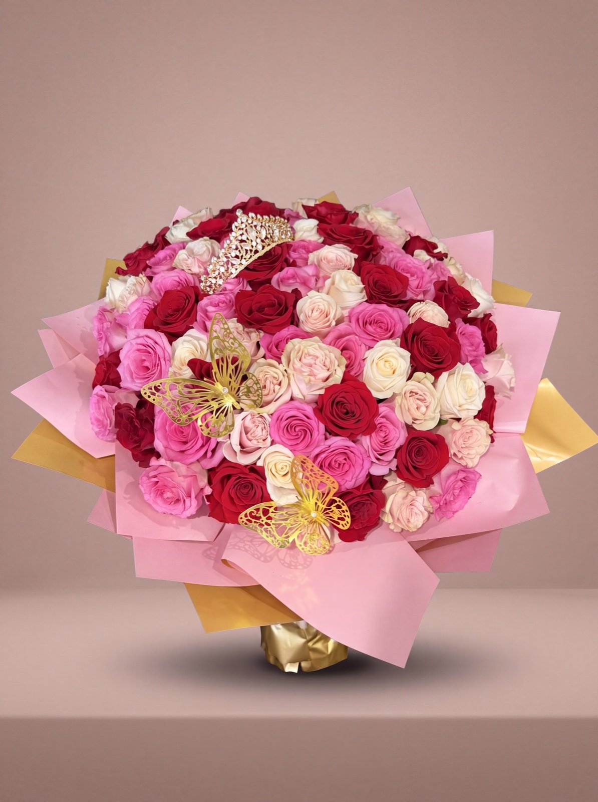 Ramo de 100 rosas rosadas, rojas y crema con tiara de cristales y mariposas doradas