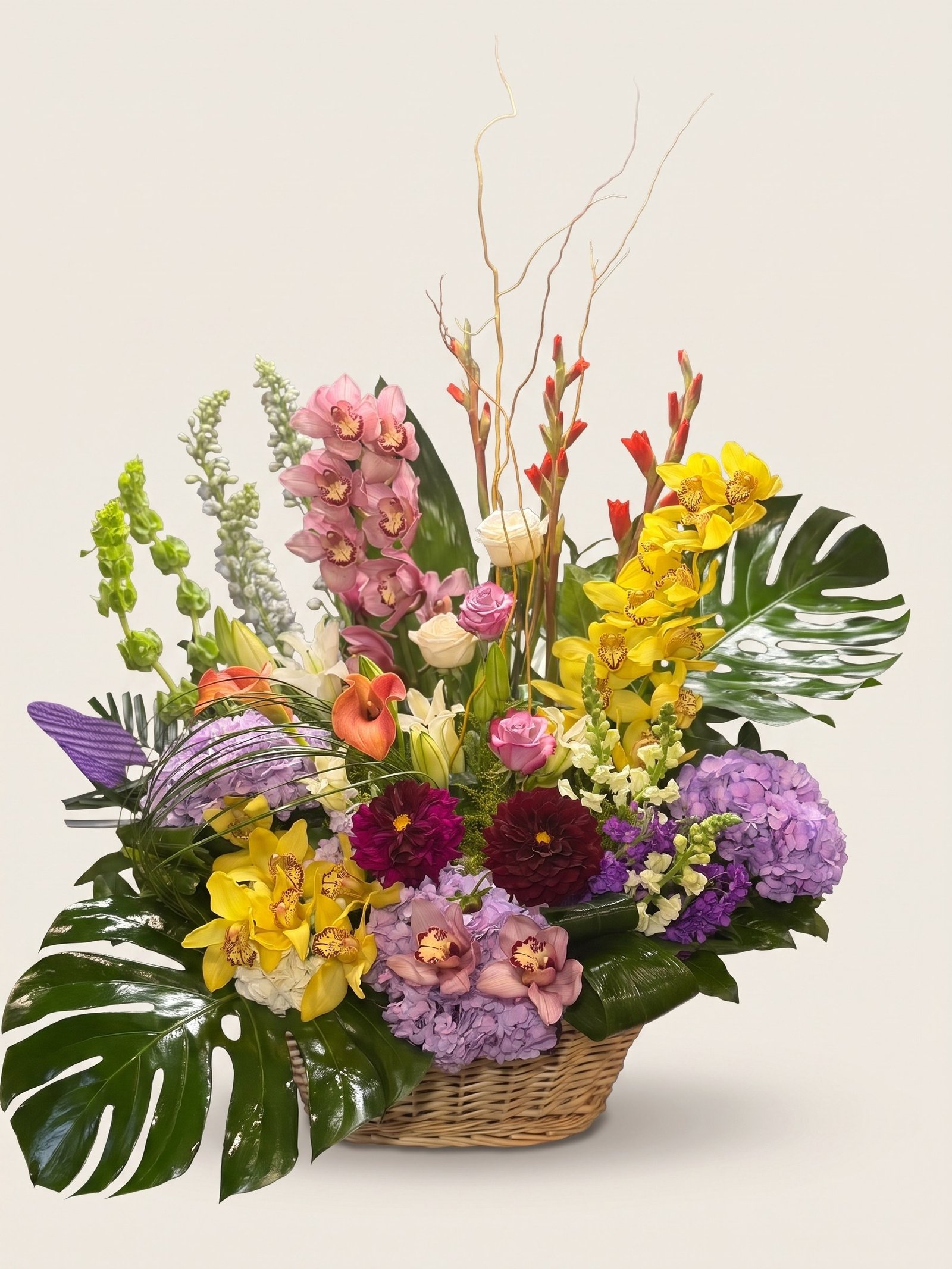 Large wicker basket of pink and yellow cymbidium orchids, gladiolus, dahlias, calla lilies, and bells of Ireland, second view