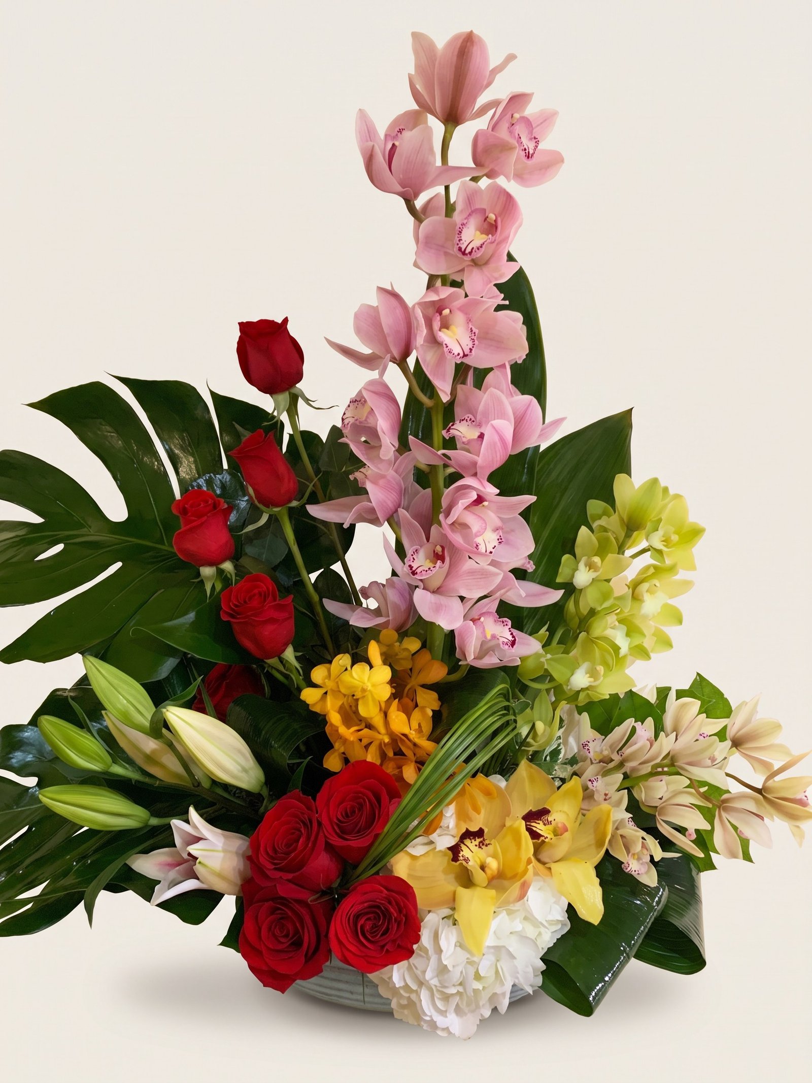 Orquídea cymbidium rosa alta con rosas rojas, cymbidium amarillo y lirios blancos